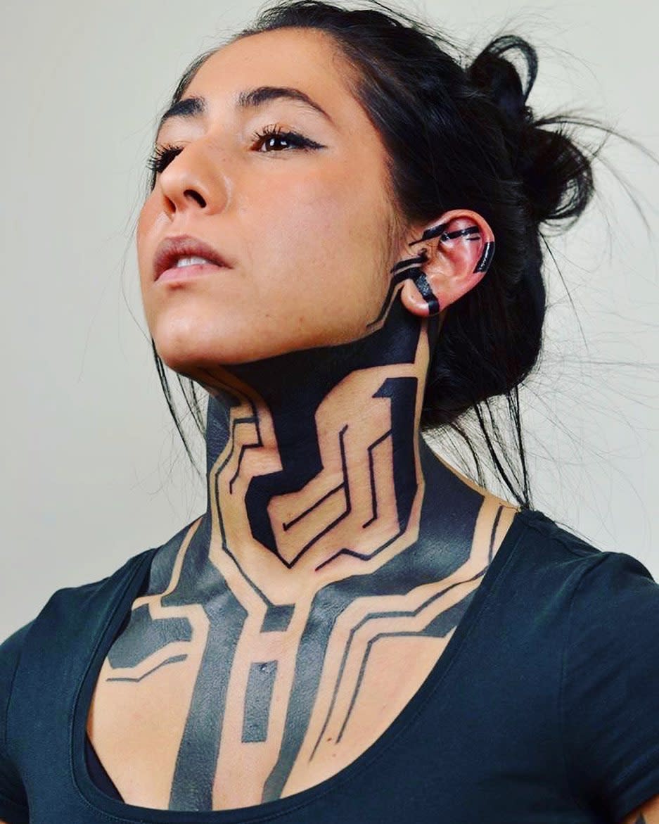 Striking cyberpunk tattoo covering neck and chest, featuring bold geometric and circuit patterns